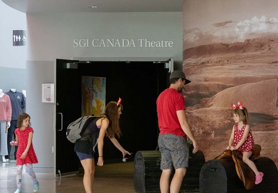 Family playing in front of SGI Canada Theatre