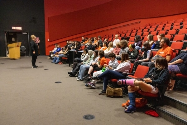 Students attend an educational presentation in a theatre.